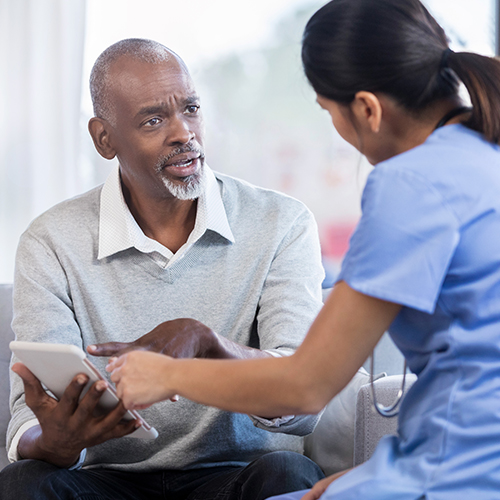 Older male patient with a concerned expression speaking with a health care provider