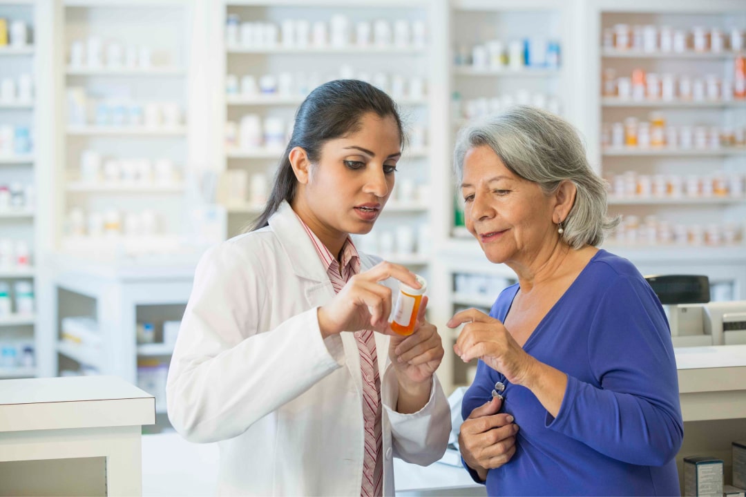 A pharmacist explains the label of a medication bottle to an older patient